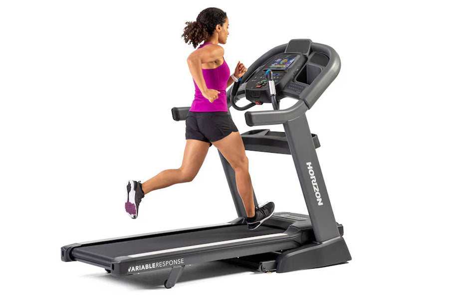 Woman running on black Horizon 7.8 AT treadmill, wearing magenta tank top and black shorts, on white background