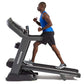 Man running on gray Horizon 7.8 AT treadmill, wearing blue tank top and black shorts, on white background