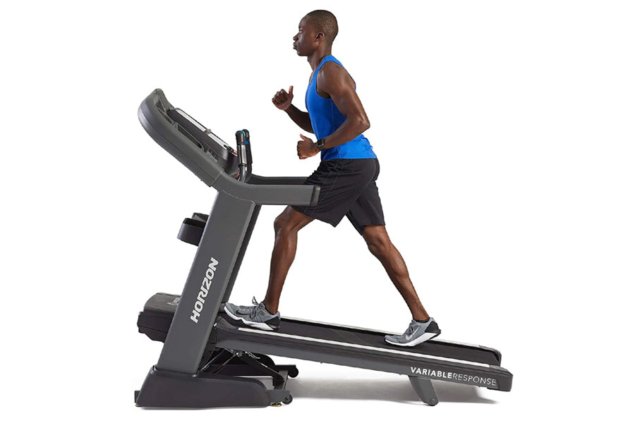 Man running on gray Horizon 7.8 AT treadmill, wearing blue tank top and black shorts, on white background