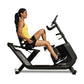 Woman in yellow tank top and black shorts seated on black Horizon recumbent exercise bike with foot pedals and handlebar grip