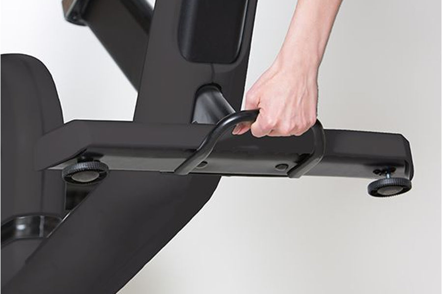 Black recumbent exercise bike with model's hand adjusting the resistance dial on horizontal handlebar