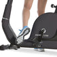 Person exercising on black Horizon Comfort R recumbent bike with blue and white sneakers, showing pedal and seat detail on wh
