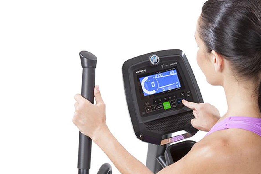 Woman wearing purple sports top using Horizon Evolve 3 elliptical machine with digital display console