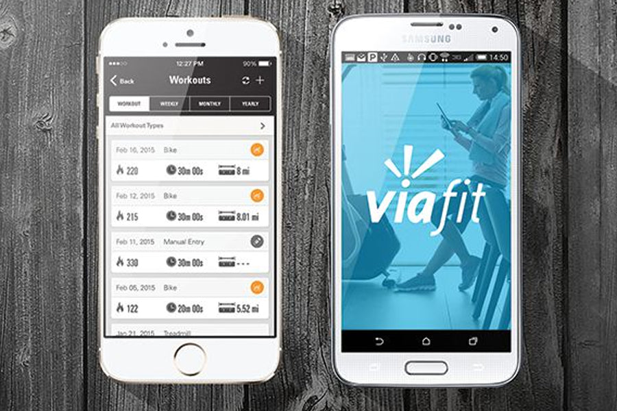 White iPhone and Samsung phones displaying fitness app workout history and Viafit logo on wooden background