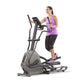 Woman wearing purple tank top and black capris using gray and black elliptical machine with digital display on white backgrou