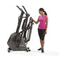 Woman in pink sleeveless top using black Horizon Evolve 5 elliptical machine on white background