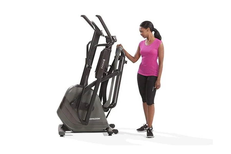 Woman in pink sleeveless top using black Horizon Evolve 5 elliptical machine on white background
