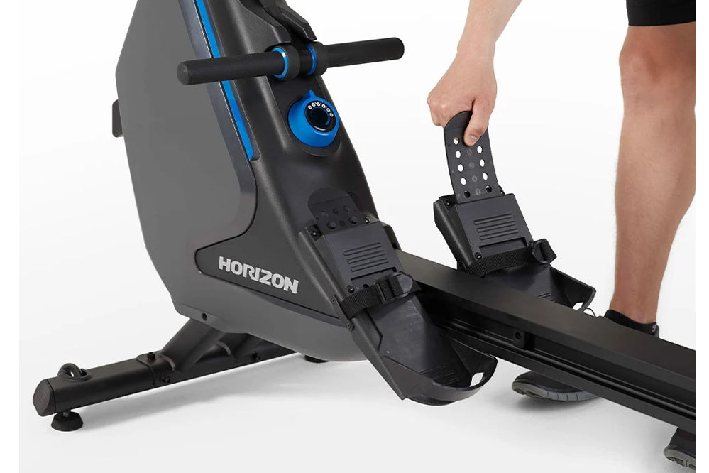 Horizon Oxford 3 rowing machine with gray and black frame, blue accents, and digital display, shown with model using foot ped