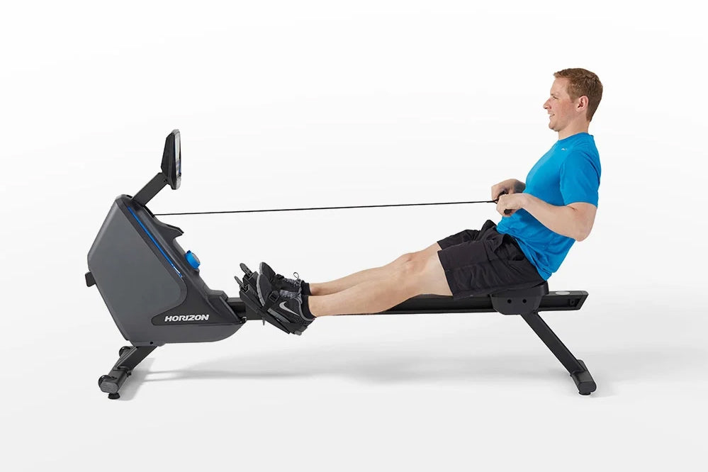 Man in blue shirt using Horizon Oxford 3 rowing machine with black seat and gray frame on white background