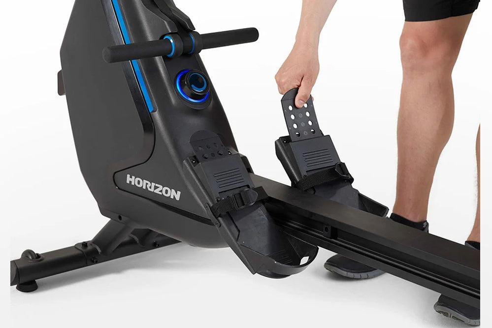 Horizon Oxford 6 rowing machine with black frame and blue accents, shown with person's legs and feet on pedals