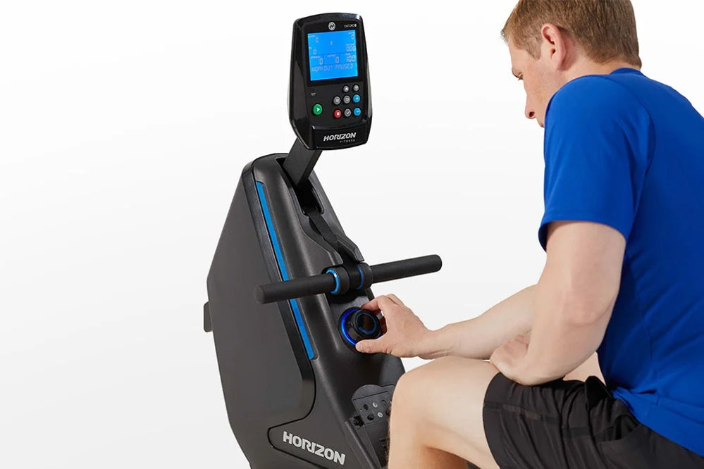 Man in blue shirt using black Horizon rowing machine with blue accents and digital display screen