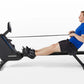 Man in blue shirt and black shorts using black Horizon Oxford 6 rowing machine with extended arms pulling resistance cord