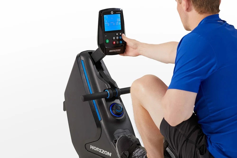 Man in blue shirt using black Horizon rowing machine with digital console display showing workout metrics