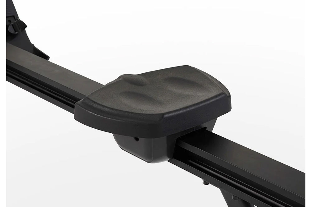 Black padded seat with contoured cushion on rowing machine frame, white background
