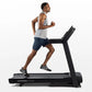 Man running on black Horizon T101 folding treadmill, wearing gray tank top and navy shorts