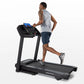 Man running on black Horizon T101 folding treadmill with blue touchscreen display against white background