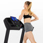 Woman wearing black sports bra and gray shorts running on black Horizon T101 folding treadmill with digital display against w
