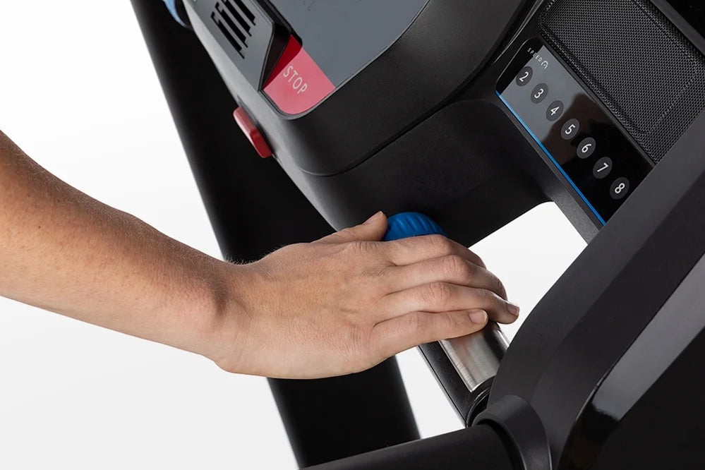 Hand adjusting blue incline button on black Horizon T101 folding treadmill with numbered controls