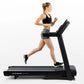 Woman running on black Horizon T101 folding treadmill wearing black sports bra and gray shorts, white background