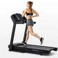 Woman running on black Horizon T101 folding treadmill with digital console, wearing gray shorts and black sports bra