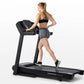 Woman in black sports bra and gray shorts running on black Horizon T101 folding treadmill with digital display against white 