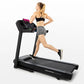 Woman running on black Horizon T101 folding treadmill with digital display, wearing black sports bra and gray shorts