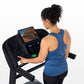 Woman wearing blue racerback tank top and black pants using black Horizon T202 folding treadmill with digital display on whit