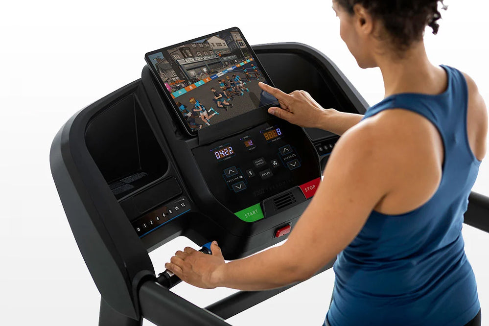 Black Horizon T202 folding treadmill with touchscreen display, worn by model in blue tank top on white background