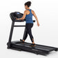 Woman running on black Horizon T202 folding treadmill with digital display, wearing blue tank top and black leggings