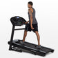 Man using black Horizon folding treadmill with digital display, worn by model on white background