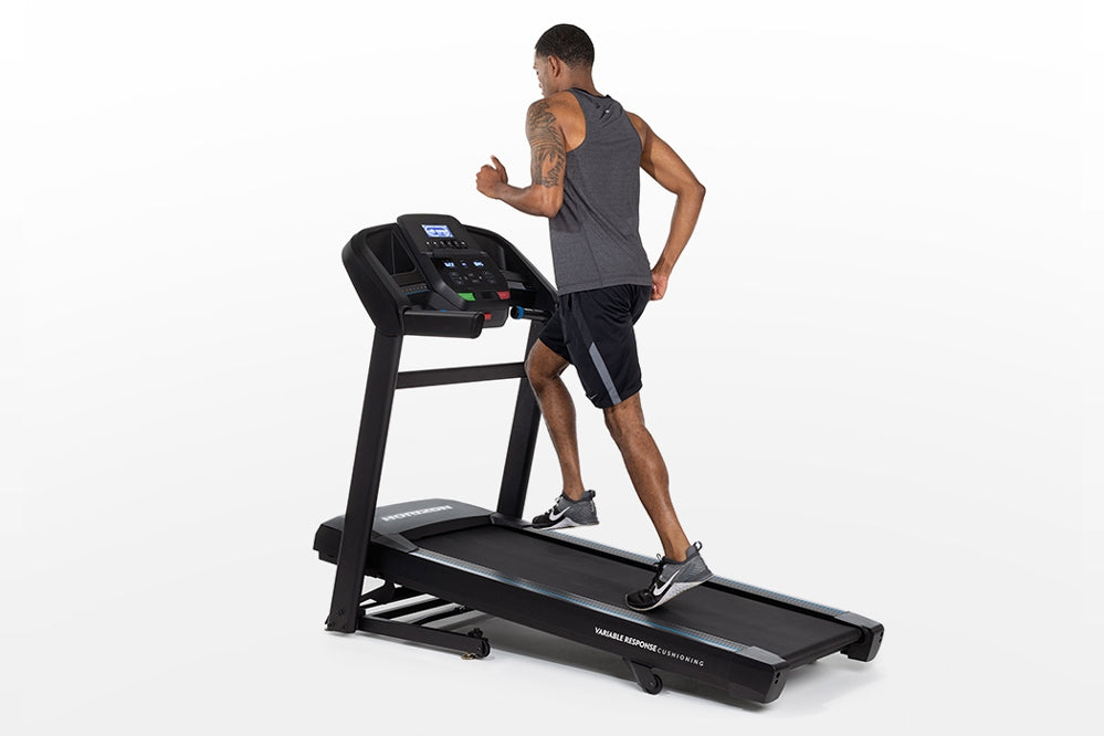 Man running on black Horizon T202 folding treadmill with digital console display against white background