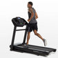 Man running on black Horizon T202 folding treadmill with digital console, shown in profile on white background