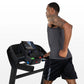 Man wearing charcoal tank top and black shorts running on black Horizon T202 folding treadmill with digital display