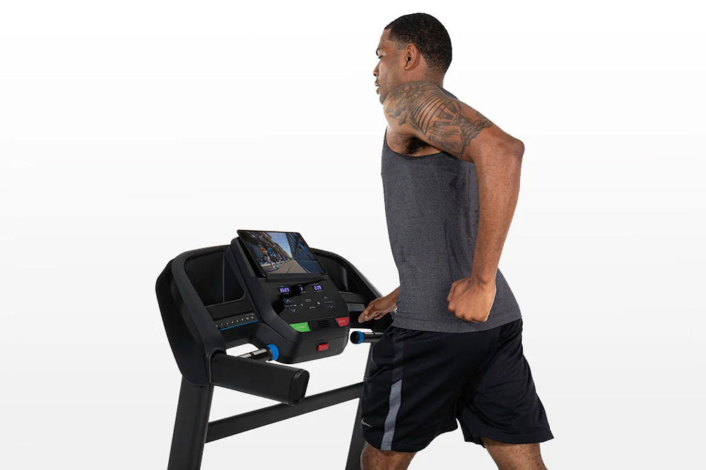 Man wearing charcoal tank top and black shorts running on black Horizon T202 folding treadmill with digital display