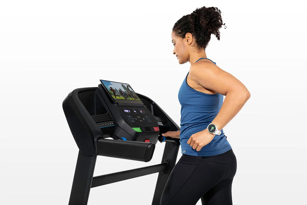 Woman in blue tank top and black leggings running on black Horizon T202 folding treadmill with digital display