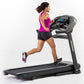 Woman running on black Horizon T303 folding treadmill with digital display, wearing magenta tank top and black shorts