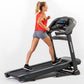 Woman running on black Horizon T303 folding treadmill with digital display, wearing red tank top and gray shorts