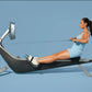 Woman in light blue athletic wear using black and silver rowing machine with attached digital screen on blue background