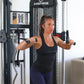 Woman using black Inspire Fitness FT1 functional trainer with cable handles, wearing black sports bra and purple leggings