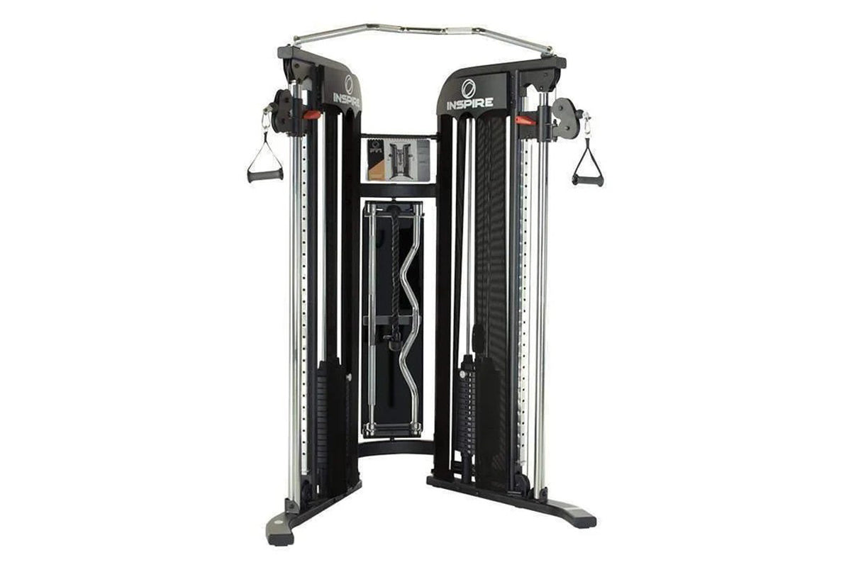 Inspire Fitness FT1 functional trainer with dual cable machine, black frame, gray top bar, and hanging handles on white backg