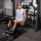 Man wearing light blue sleeveless tank top using black Inspire Fitness FT2 Pro Smith Functional Trainer in gym setting with d
