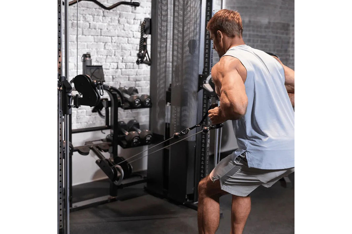Man wearing light blue sleeveless tank top and gray shorts using Inspire Fitness FT2 Pro Smith Functional Trainer in gym with