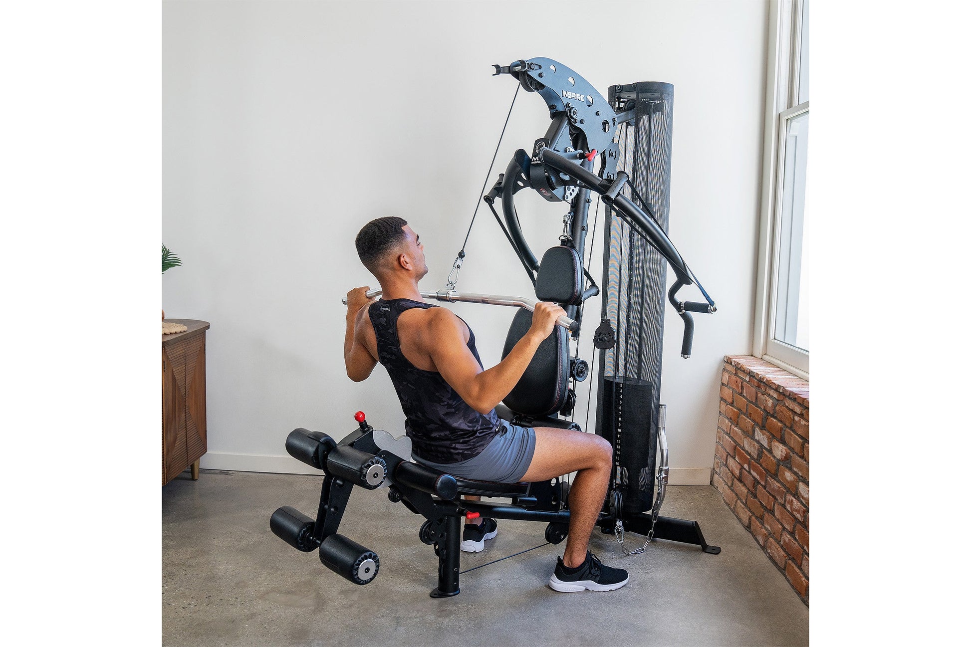 Man using blue and black multi-gym machine with leg press and chest press attachments in home gym setting