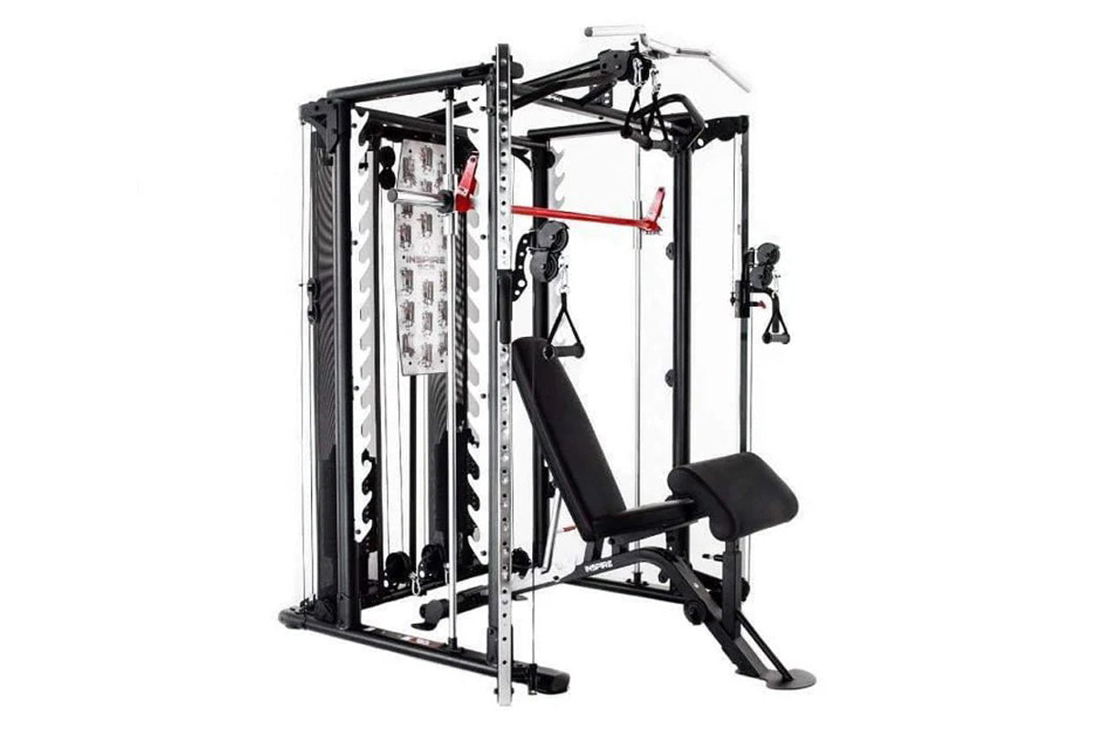 Black and silver Smith cage system with cable pulley attachments, red resistance band, and black bench seat, on white backgro
