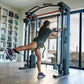 Woman using blue and black cable machine with red bar in home gym, wearing black tank top and shorts