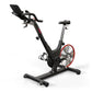 Black and red stationary indoor exercise bike with padded seat, handlebar console, and red flywheel on white background