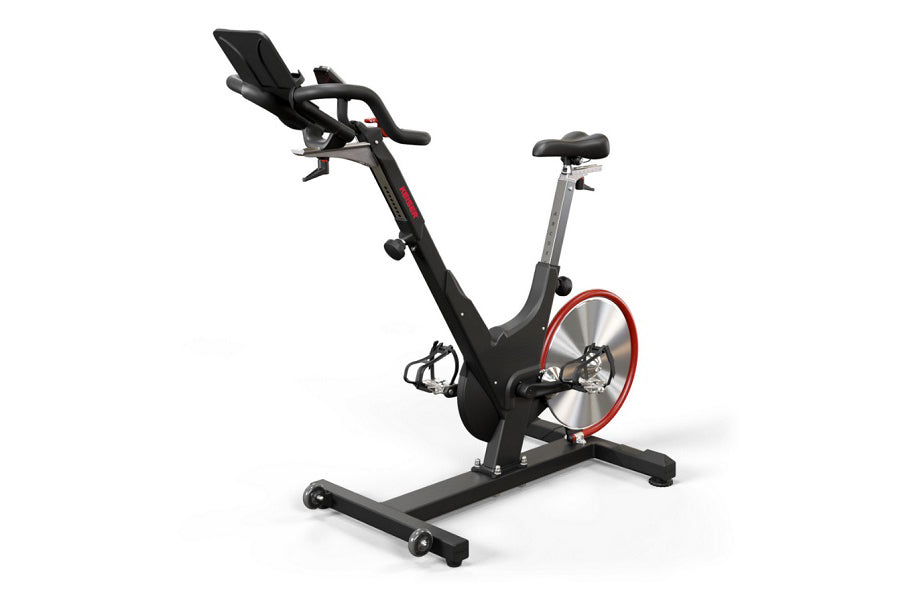 Black and red stationary indoor exercise bike with padded seat, handlebar console, and red flywheel on white background