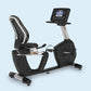 Landice R9 black recumbent exercise bike with digital console and mesh backrest on light blue background