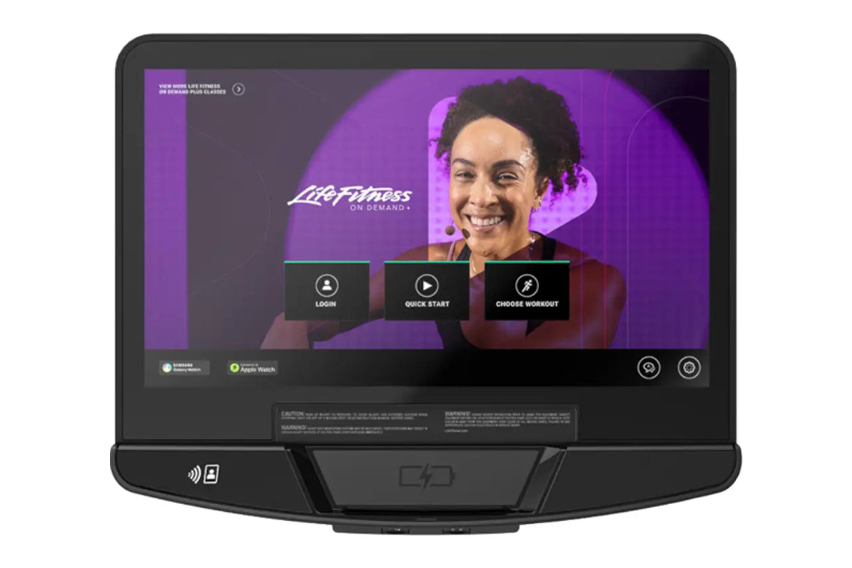 Life Fitness Atmos elliptical display console showing purple interface with smiling woman, login and workout selection button