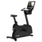 Black upright stationary bike with digital display console, handlebars, and padded seat on white background